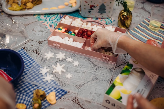 Eetbare kerstversieringen, voor taartdecoratie. Handen van de patissier close-up. Kerst vakantiesfeer. werkomgeving. creatieve puinhoop