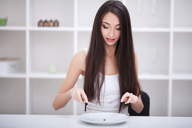 Eetpatroon. Vrouw zittend aan een tafel met groenten op een bord