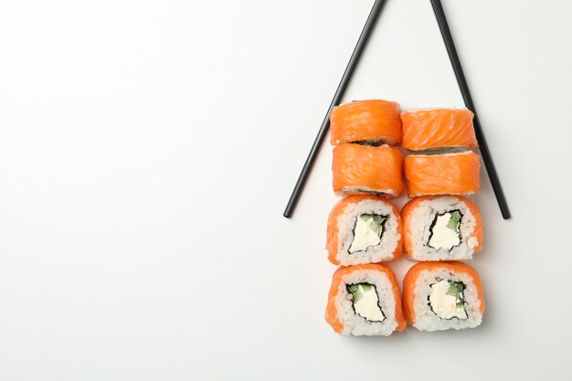 Eetstokjes en sushi rolt op witte ondergrond