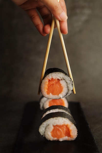 Eetstokjes en sushi rolt over donkere achtergrond