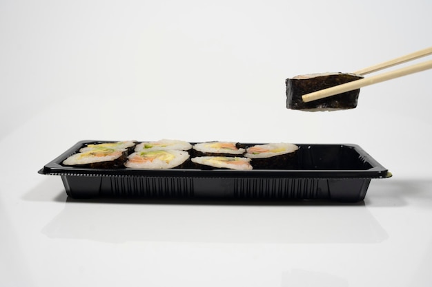 Eetstokjes pakken een stuk sushi uit een sushiset