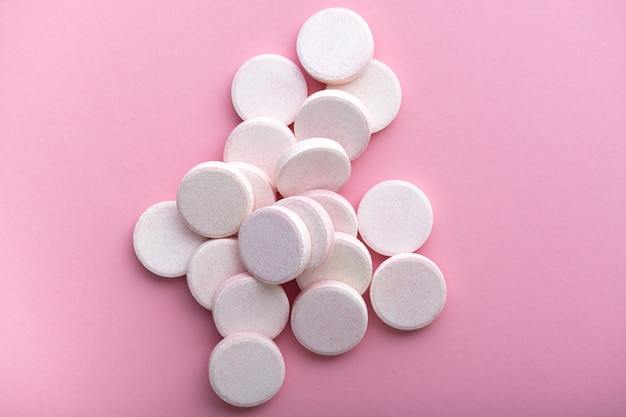 Effervescent tablets on pastel pink surface, top view