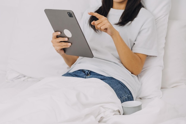 Efficient Young Millennial Girl Sitting on a Bed in the Morning Uses Laptop Computer and Eats Croissants and Drinks Coffee for Breakfast Top Down Shot