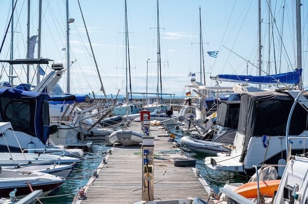 Egeïsche zeehaven met meerdere afgemeerde jachten en boten, houten pier, helder weer in nikiti, griekenland