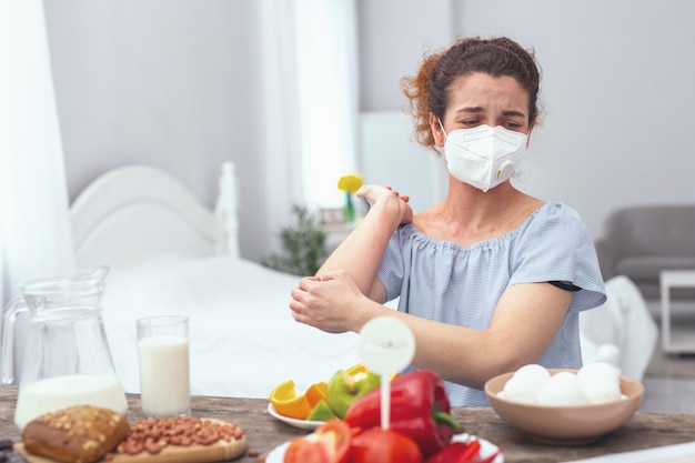 Egg allergy. young woman wearing a respiratory mask displaying symptoms of a severe egg allergy affecting her by smelling a product