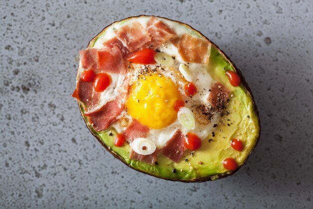 Egg baked in avocado with bacon and spring onion