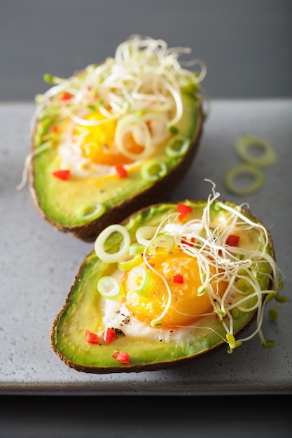 Egg baked in avocado with spring onion and alfalfa sprouts