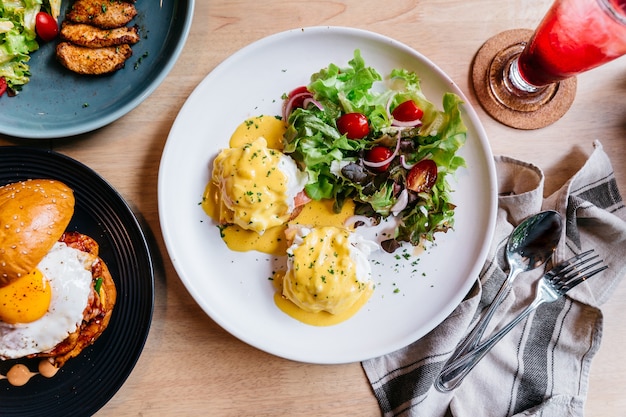 Egg benedict served with salad in white plate on wooden table for delicious breakfast and 