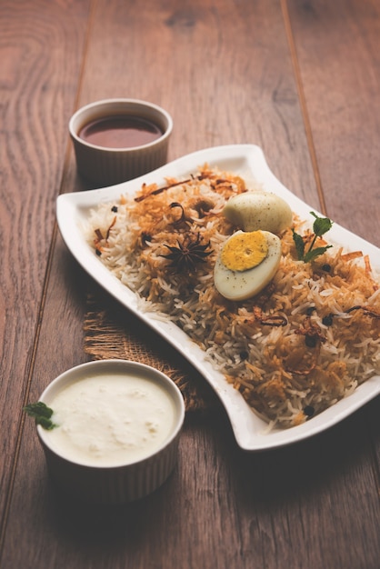 Egg Biryani - Basmati rice cooked with masala roasted eggs and spices and served with yogurt, selective focus