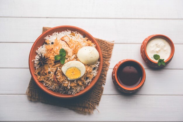 Egg Biryani - Basmati rice cooked with masala roasted eggs and spices and served with yogurt, selective focus