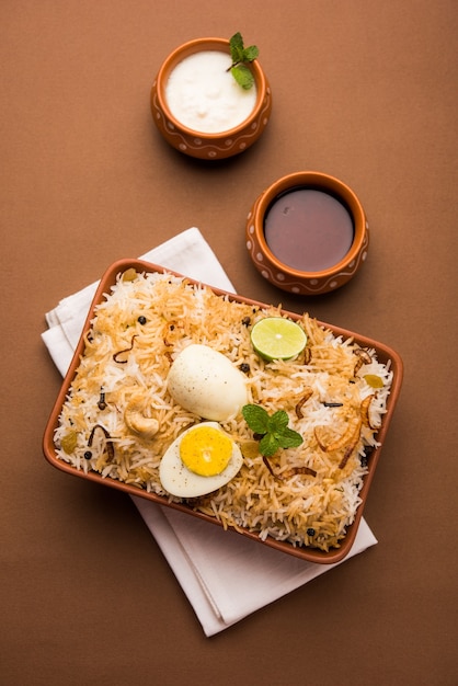 Egg Biryani - Basmati rice cooked with masala roasted eggs and spices and served with yogurt, selective focus