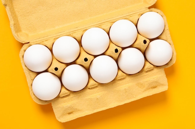 Egg box with eggs on orange background top view