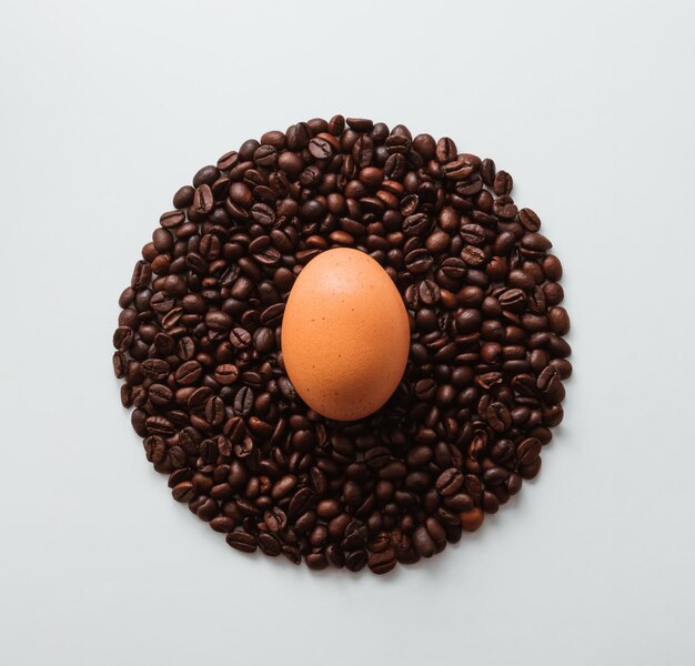 Egg and coffee roasted beans on white background Top view Easter composition Food and drink concept