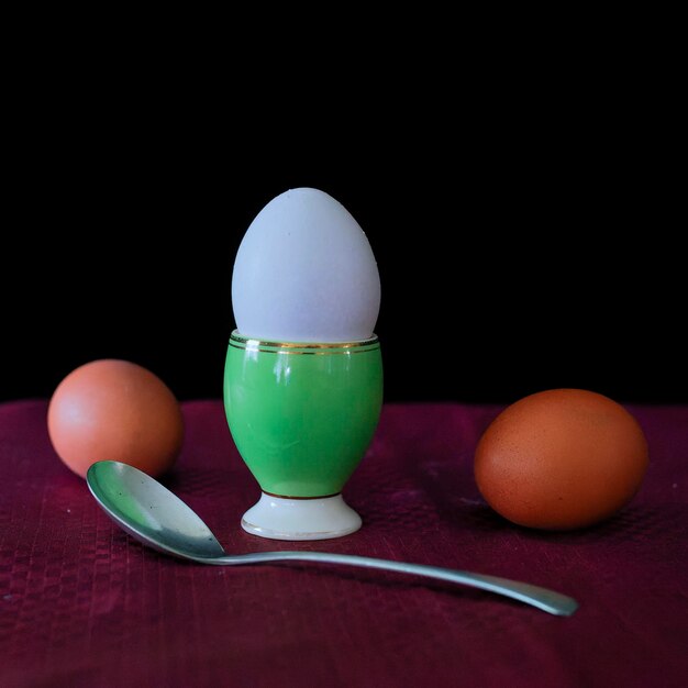 An egg in a cup with two eggs around it