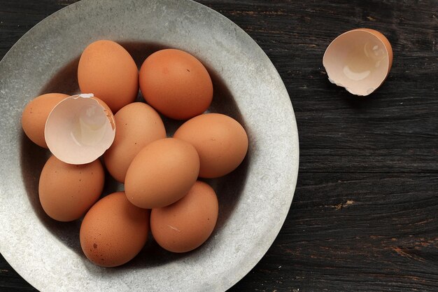 Egg and egg shell on rustic plate above wooden table