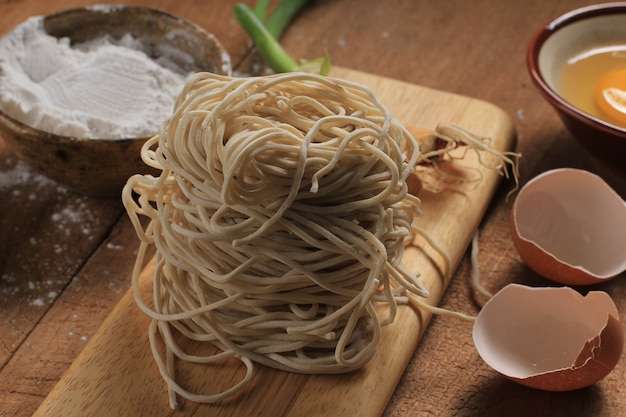 Photo egg, flour, and raw asian noodle on wooden board