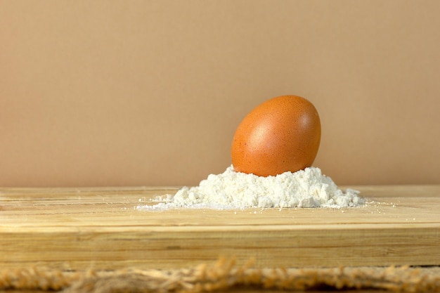 egg and flour on a wooden board, brown background