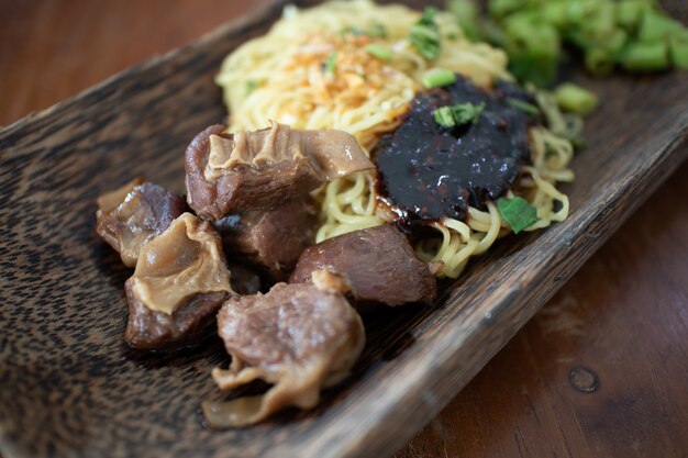 豚肉と醤油の卵麺は木製のボウルで提供しています。