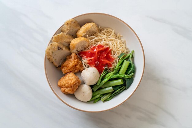 Photo egg noodles with fish balls and shrimp balls in pink sauce yen ta four or yen ta fo