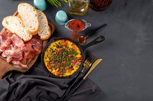 Frittata di uova con salsiccia e condimenti in una padella in ghisa vista dall'alto spazio libero per il testo.