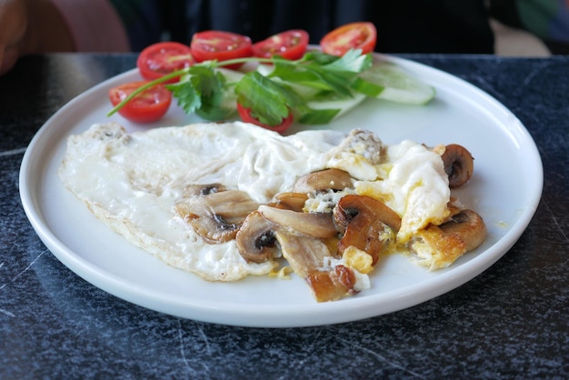 朝食用の白い皿にキノコとチェリートマトの卵オムレツ