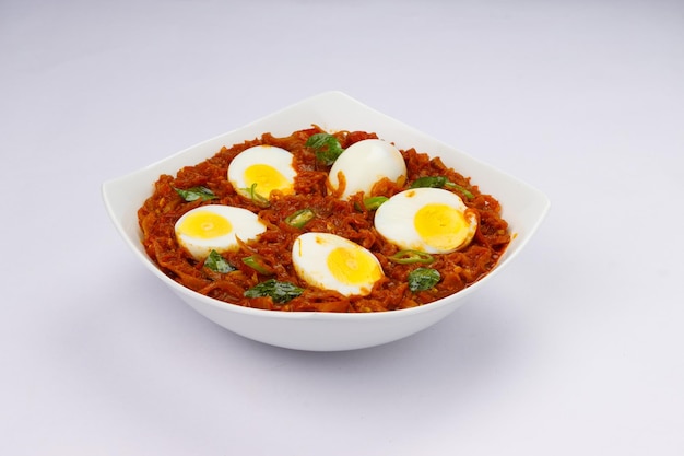 Egg roast or indian egg masala curry spicy red egg roast arranged in a white ceramic bowl