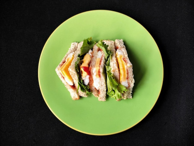 Egg sandwichs on green plate and black background high angle view of breakfast on table