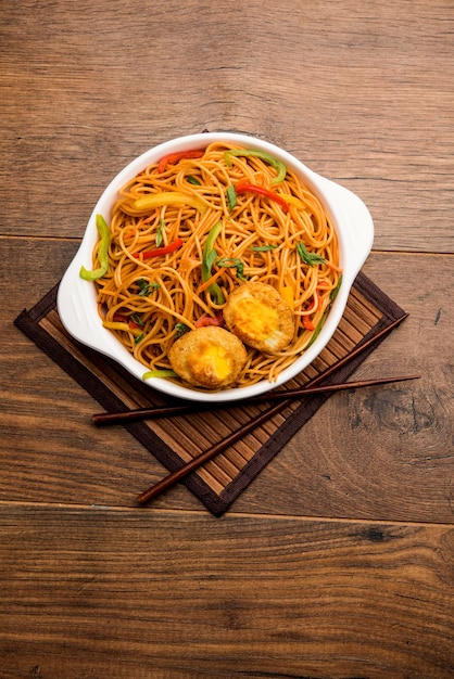 Egg Schezwan of Hakka-noedels, populair Indo-Chinees eten geserveerd in een kom met eetstokjes