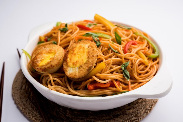 Egg Schezwanor hakka noodles, popular indochinese food served in a bowl with chopsticks. selective focus