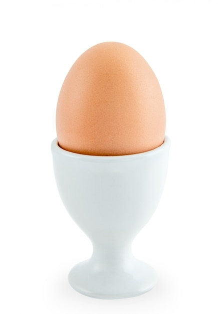 Egg standing on a cup isolated on white