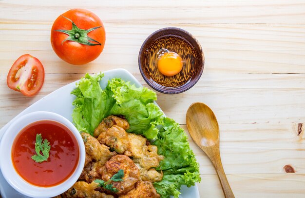 egg steam with fried and saucechilli, lettuce and tomato on table