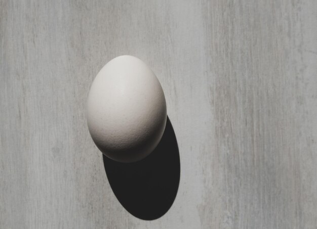 テーブルの上の卵。灰色の背景に最小限の白いイースターエッグ、フラットレイ。ミニマリズム。単純