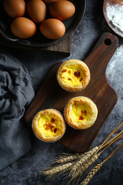 Egg tarts on wooden board on dark background