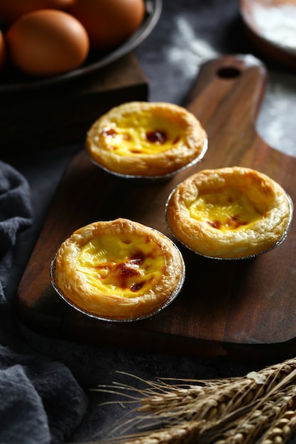 Egg tarts on wooden board on dark background