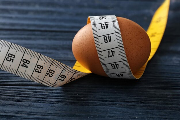 Egg with measuring tape on wooden table