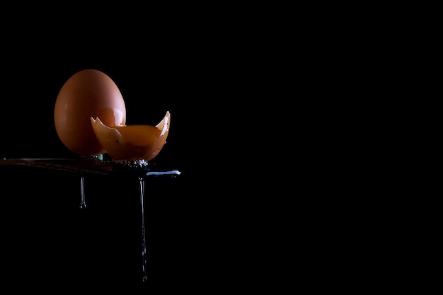 Egg with yolk and drops on the edge of a wooden table