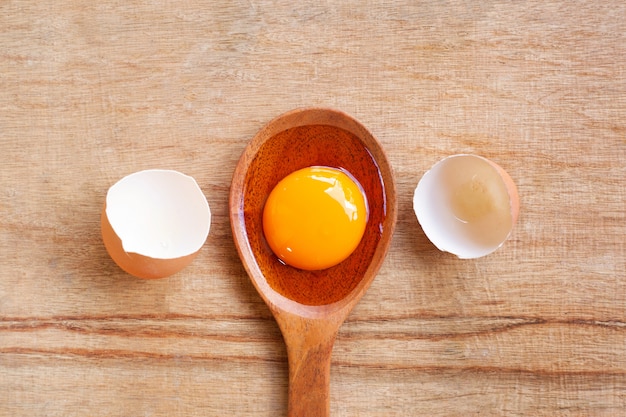 Egg yolk on wooden spoon, Wooden background.