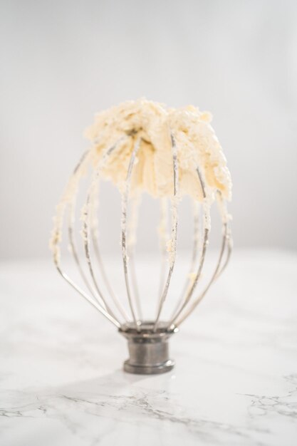 Eggnog buttercream frosting on a whisk from an electric kitchen mixer.