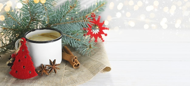 Eggnog with cinnamon anise and nutmeg on wooden table near branches of Christmas tree