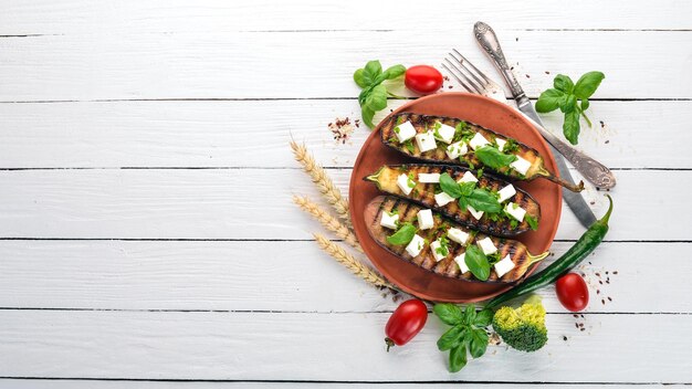 Eggplant grilled with feta cheese and basil Healthy food On a white wooden table Top view Free space for text