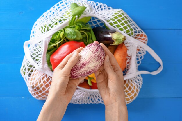 Eggplant in hand, vegetable basket, summer harvest, top view