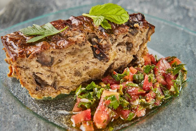 Eggplant pie with tomato sauce on glass plate.