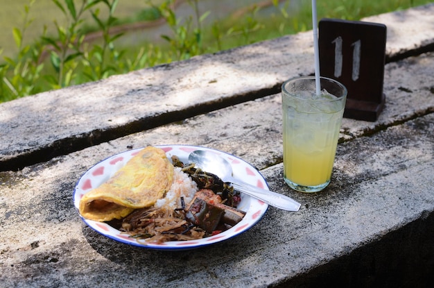 Eggplant rice noodles and omelet served with fresh orange juice