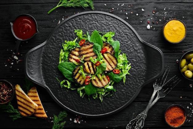 Салат из баклажанов со шпинатом и капустой на черной тарелке Веганская еда Вид сверху Деревенский стиль