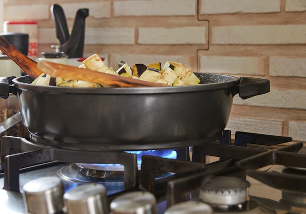 Eggplants are fried in pan on gas stove in the kitchen according to recipe from the Internet.