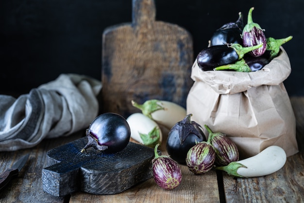 Eggplants of different colors and different grades on a wooden table.