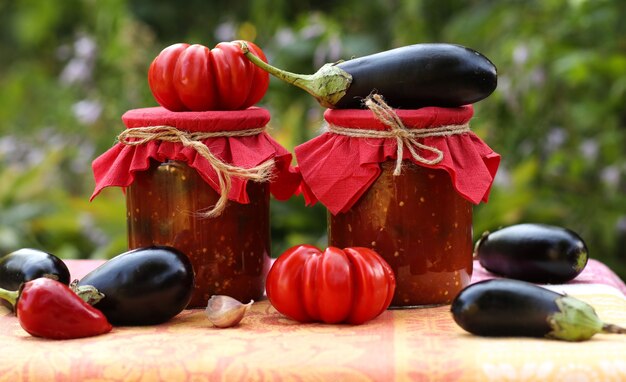 Eggplants in tomatoes in jars are located on a table in the garden