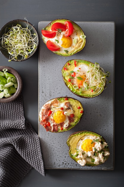 Photo eggs baked in avocado with bacon cheese tomato and alfalfa sprouts