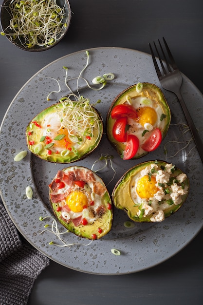 Eggs baked in avocado with bacon cheese tomato and alfalfa sprouts