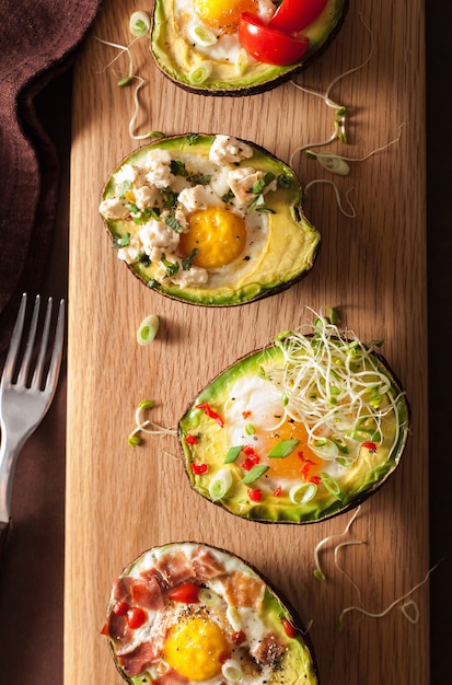 Eggs baked in avocado with bacon cheese tomato and alfalfa sprouts